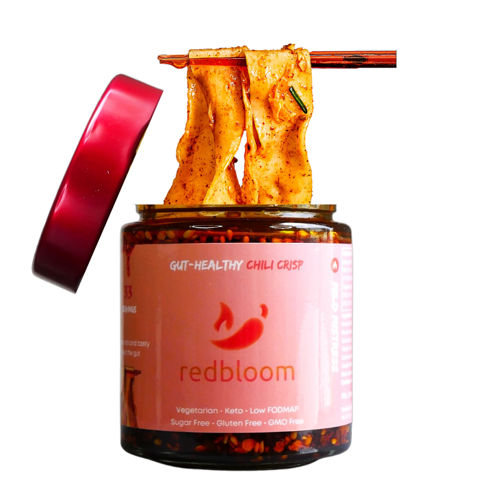 Chopsticks lifting tofu out of a jar labeled 'gut-healthy chili crisp red bloom.'