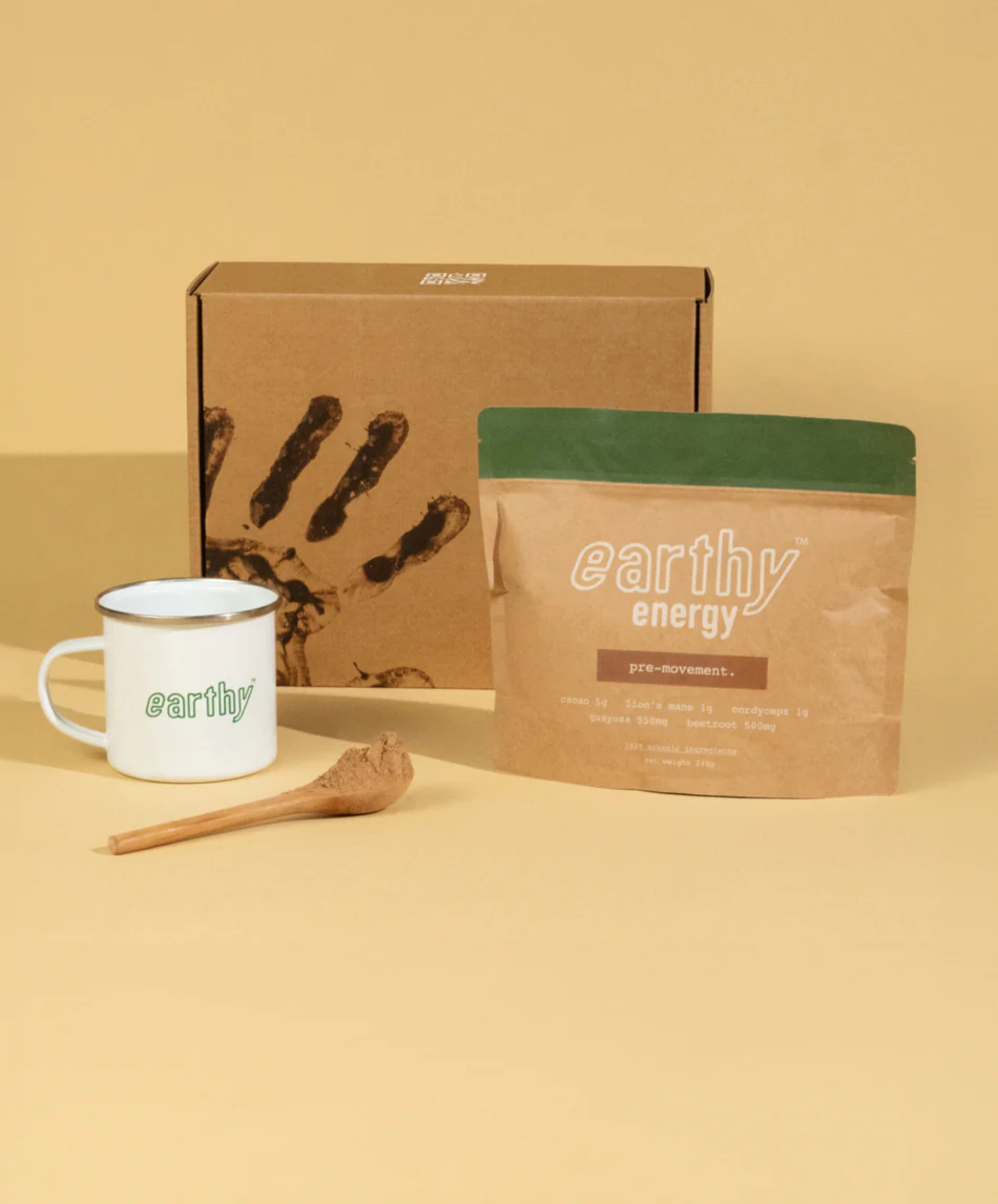 Branded mug, package of 'earthy energy' product, and wooden scoop on a yellow background.