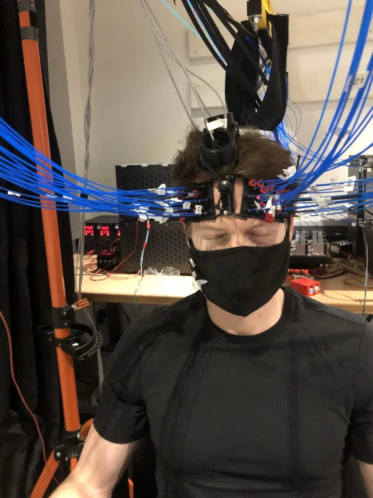 Bryan Johnson wearing a high-tech brain-monitoring headset with dozens of blue sensor cables as part of the Blueprint Project—illustrating his use of neurofeedback and cutting-edge technology to reverse aging and optimize cognitive health.
