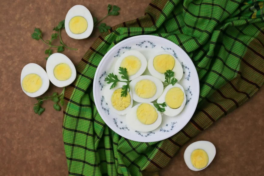 A plate of boiled eggs, halved to reveal nutrient-rich yolks, presented on a green plaid cloth—eggs are a natural source of choline, vital for methylation and cellular function, contributing to longevity and age reversal.