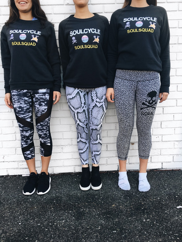 Three women wearing Embify made SoulCycle gear. Bella+Canvas sweatshirts are screenprinted and say Soul Cycle, along with three patches across each and embroidery under the patches. 