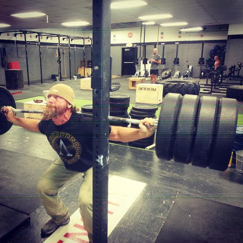 man training in the gym squatting with heavy weights