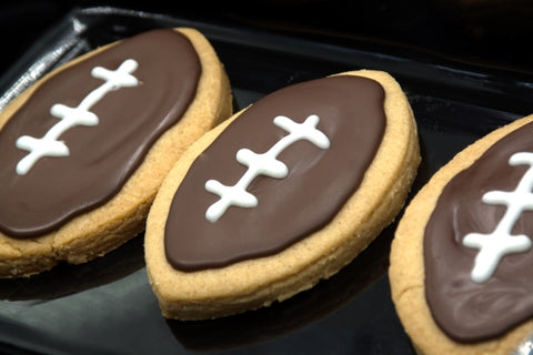 hand-taking-cookie-from-plate-football-shape-cookies-plate-home-made-cookies-concept-american-sport-concept-super-bowl-party-cookies
