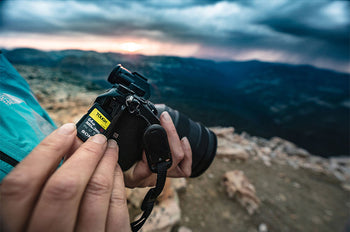 Photographer inserting Sony Tough V90 SD card into camera during sunset