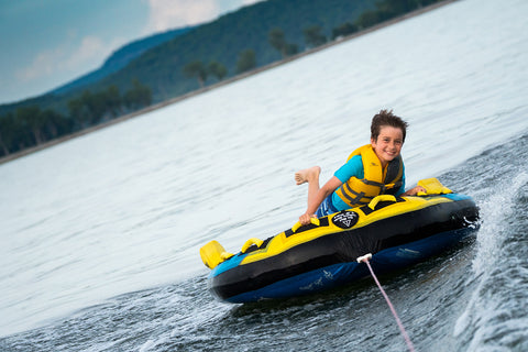 Young boy on a tube pulled behind a boat