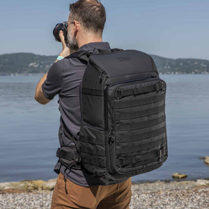 photographer shooting on a beach with Tenba Axis V2 32L Backpack