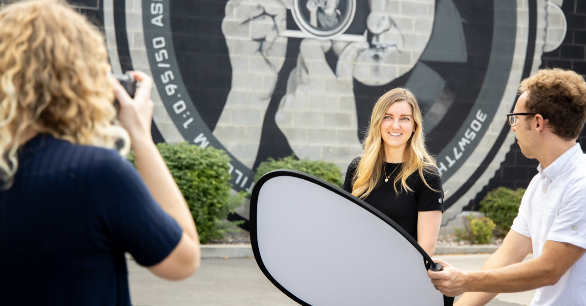 photographer using assistant to hold reflector for light on model