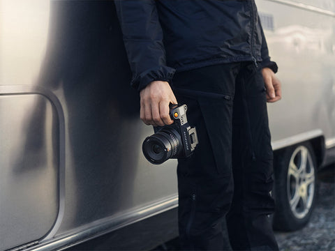 photographer holding camera near a car