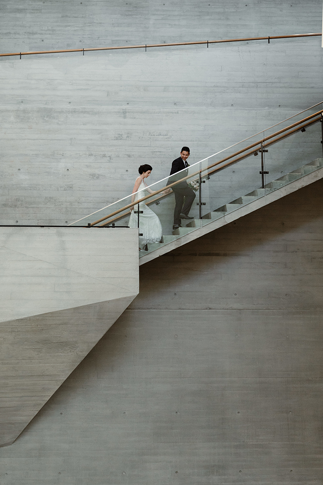 Chelsea Fabrizio photography image of bride and groom walking up stairs in large building 
