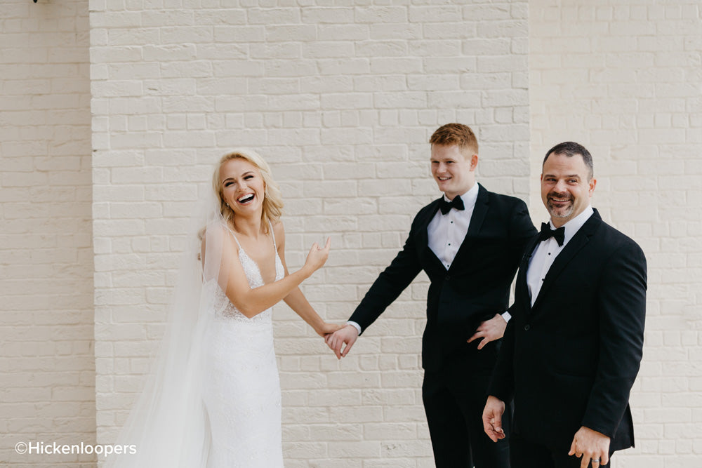 bride with family with white brick background by scott hickenlooper