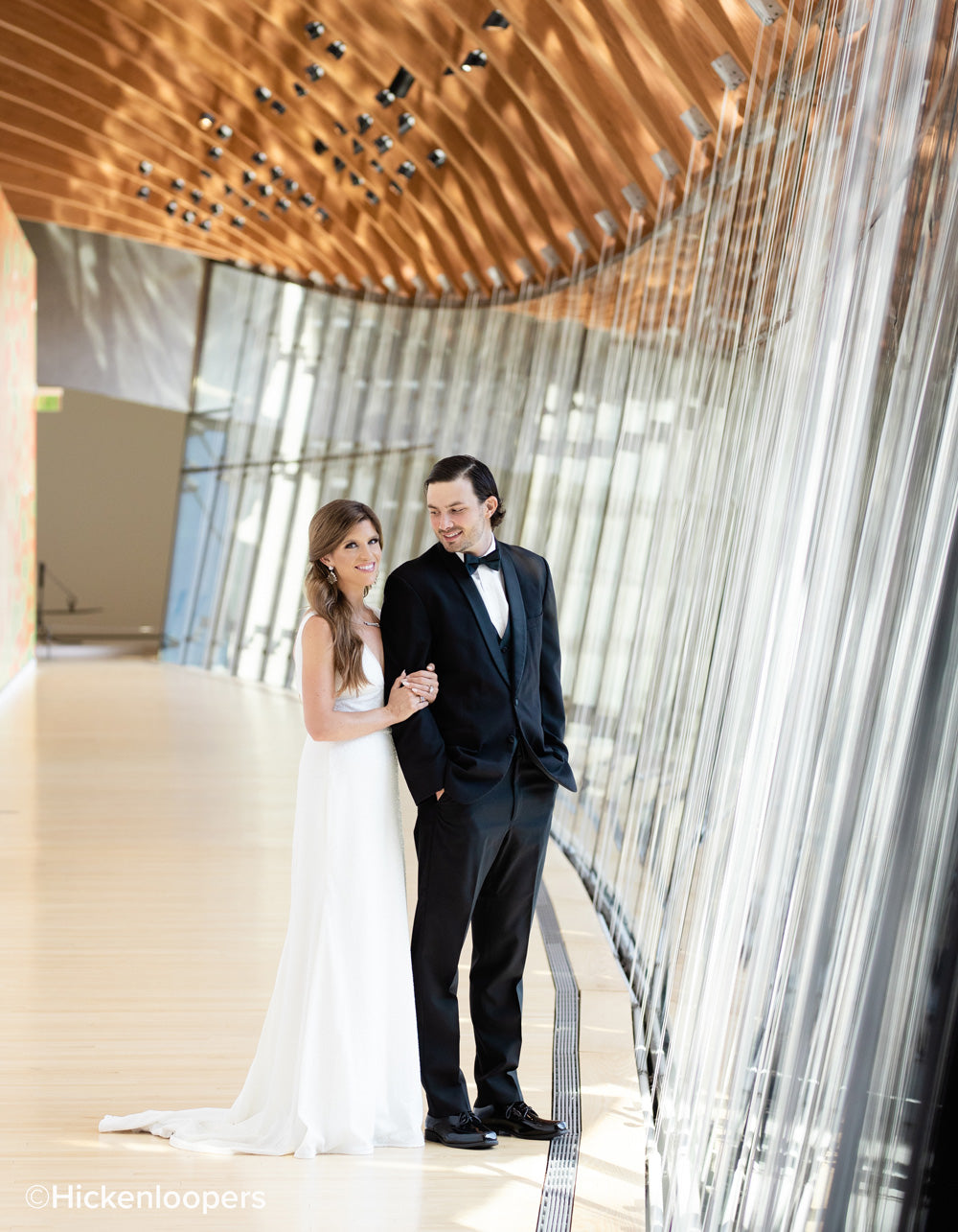 bride and groom in building surrounded by glass paneling by scott hickenlooper