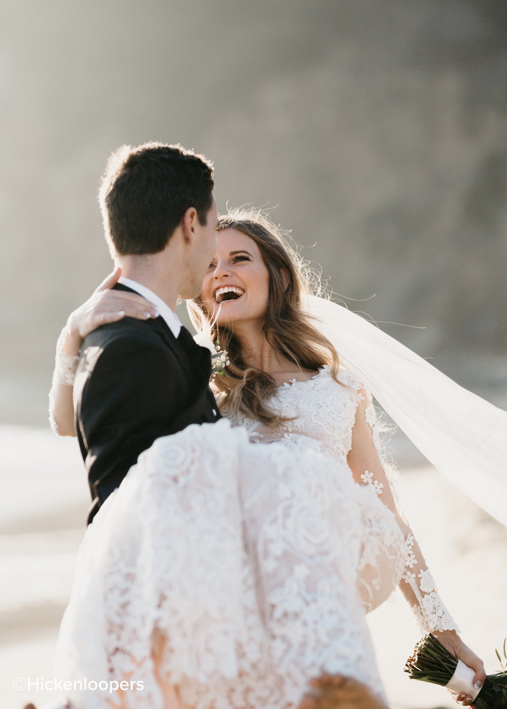 bride in groom's arms with wedding dress helping reflect light on face by scott hickenlooper