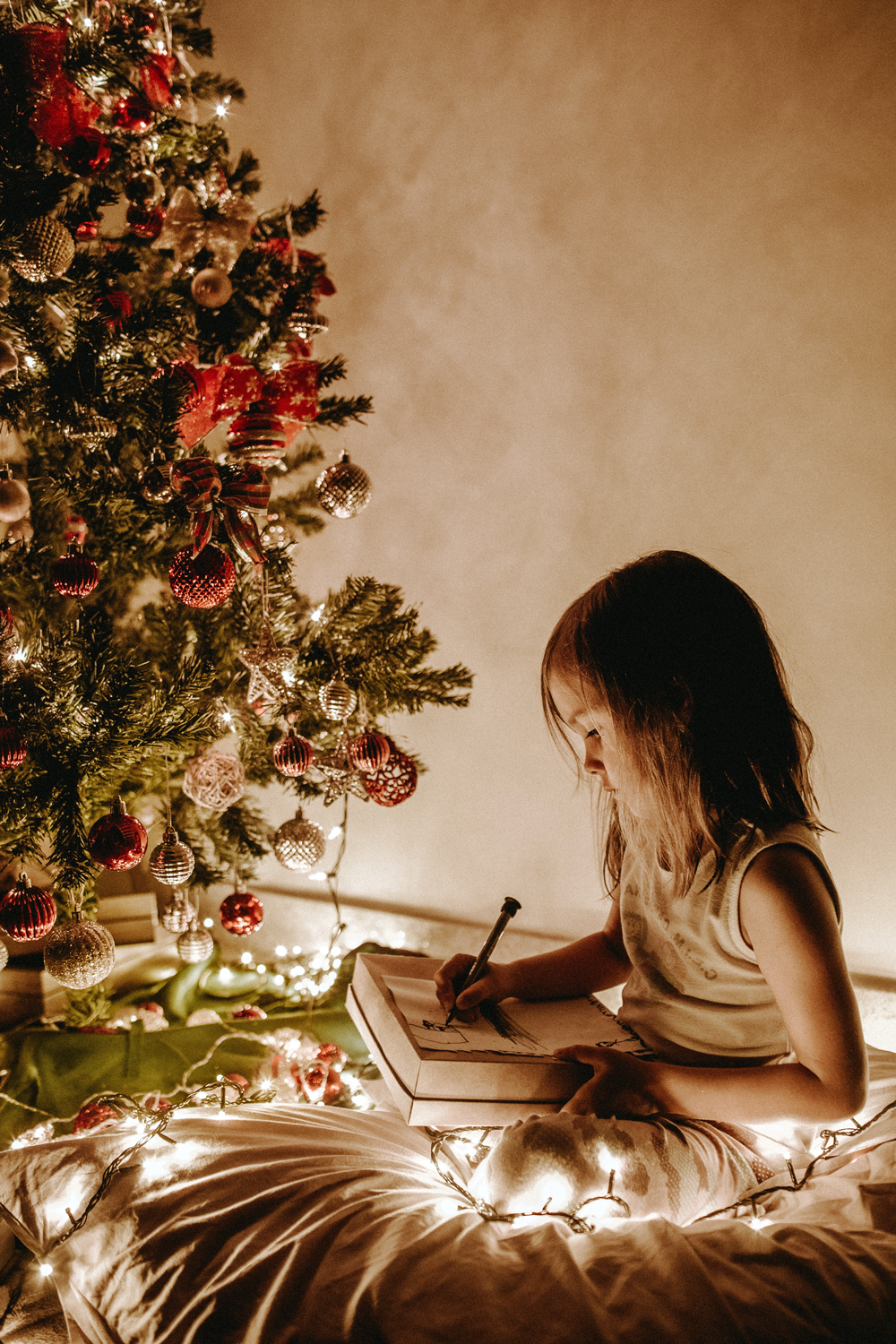 little girl sitting by christmas tree