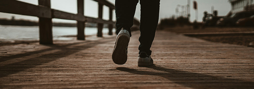 Close up of legs of man walking on pier
