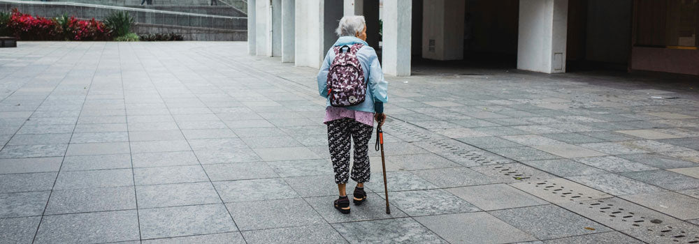 Senior woman walking in an urban environment using a cane