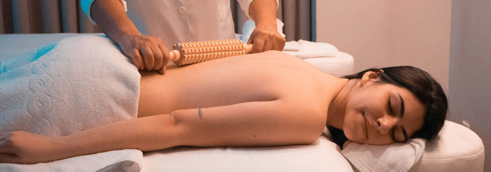 Therapist giving a massage to a young woman with a rolling massage device