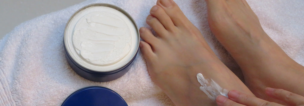 Woman putting lotion on her feet