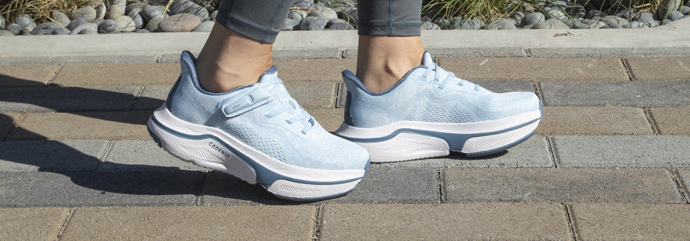 Woman wearing a pair of light blue adaptive shoes by Cadense