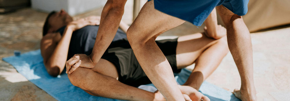 Yoga Teacher giving student a hip extension stretch assist