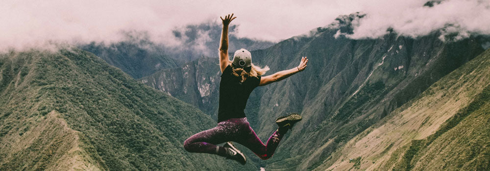 Young woman jumping in the air with beautiful mountain in the background