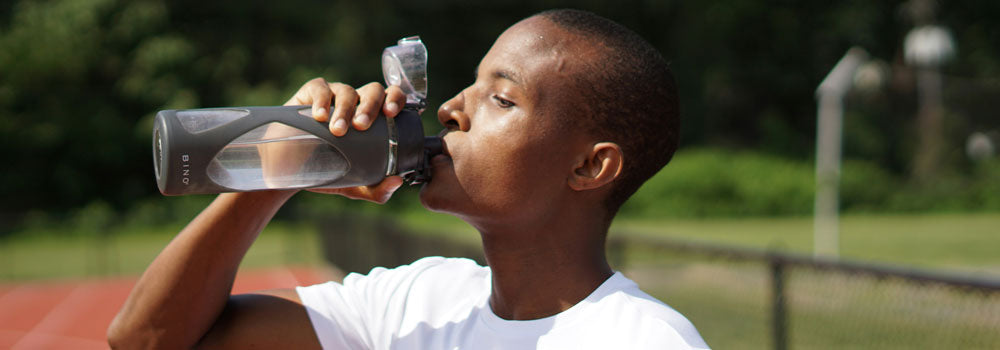 Young athlete drinking water out of a sports water bottle
