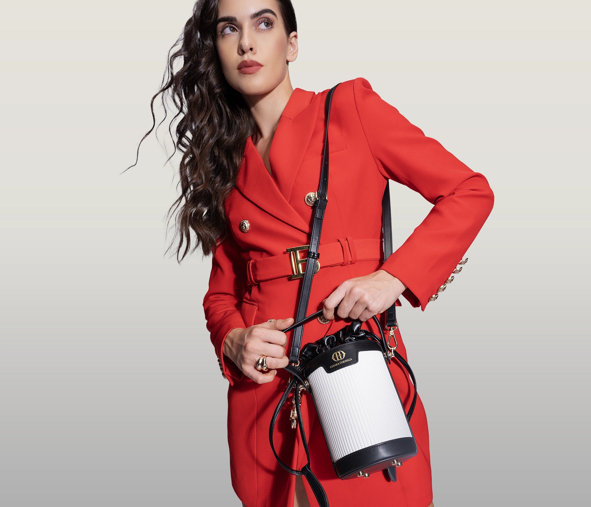 A model in red outfit holding a blaise bucket bag in black color