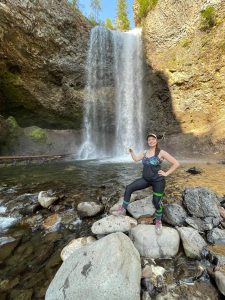 Woman standing in front of a tall waterfall, smiling