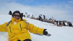 Outdoor Adventures - Woman in yellow parka surrounded by penguins