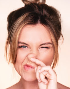 portrait of a woman picking her nose with her hand. She has brown hair and is wearing lipstick.