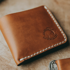 A slim leather wallet with two compartments, open to reveal cash and cards inside.