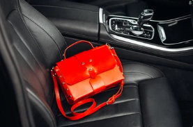 Red Italian Leather Handbag lying on the black leather seat of a stylish sportscar