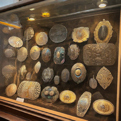 Image of a display cabinet showing a collection of vintage belt buckles