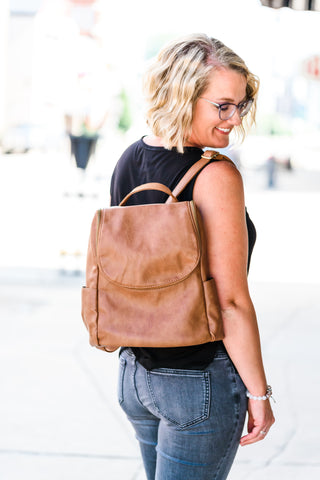 Woman carrying her light brown leather backpack