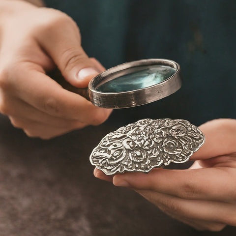 Image of a valuer inspecting a vintage silver belt buckle