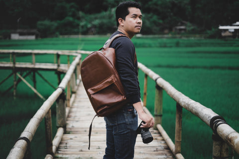 Photographer wearing a brown leather backpack on one shoulder