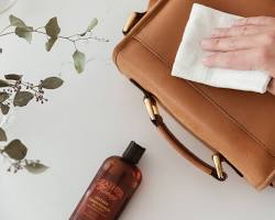 hand gently wiping a leather bag with a leather wipe