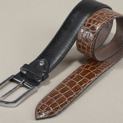 Reversible belt with one side featuring smooth black leather and the other side with a brown crocodile-embossed pattern, both with a matching silver buckle, providing versatility and style options.