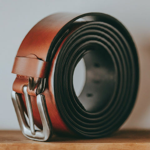 A leather belt properly rolled and stored in a dust bag for safekeeping.