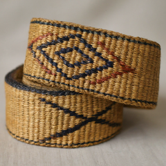 Woven belt made from natural straw fiber with a geometric pattern in contrasting colors, perfect for adding texture to summer outfits.