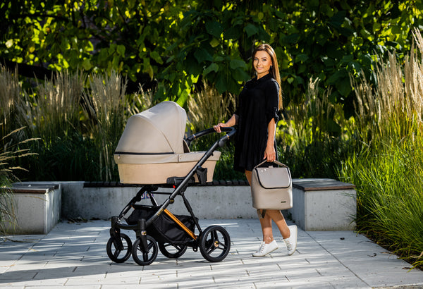An elegant woman in a park, holding the handle of the Kunert LAZZIO Stroller
