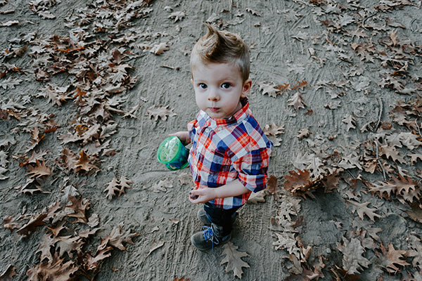 Kids love the environment: Child walking on dusty road surrounded by Autumn/Fall leaves