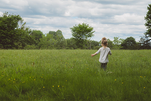 Kids care for the planet: Toddler walking through green grassy field