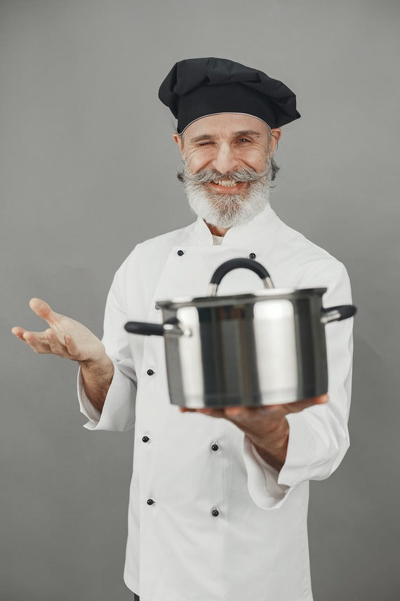 An image of an elderly chef in a chef outfit holding a pot with a black chef hat