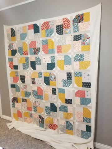 Quilt blocks and sashing strips on batting hanging from wall