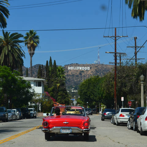 Classic car driving down road with Hollywood sign in the background