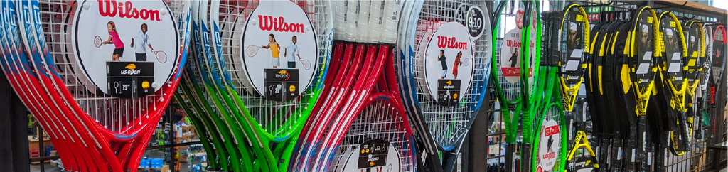 A close up of tennis rackets hanging on a wall.