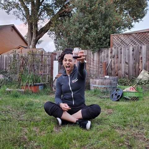 V sitting in the grass holding a beer. 