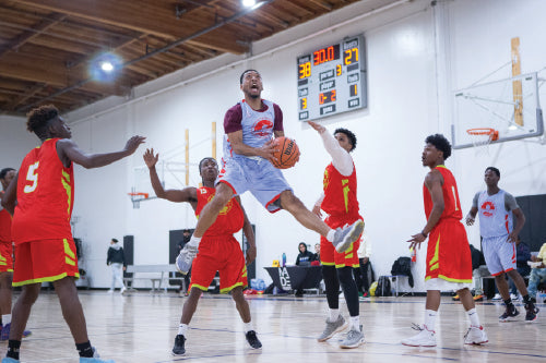  A man mid-air about to shoot a ball into the basket.