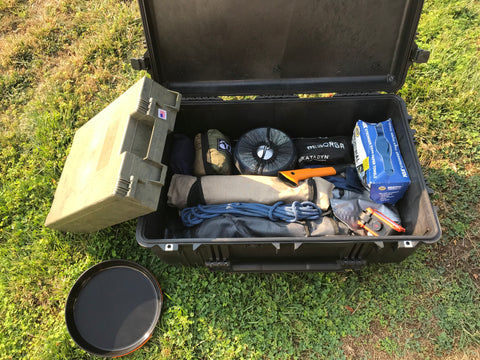 Box filled with supplies including an ax, stove, etc.