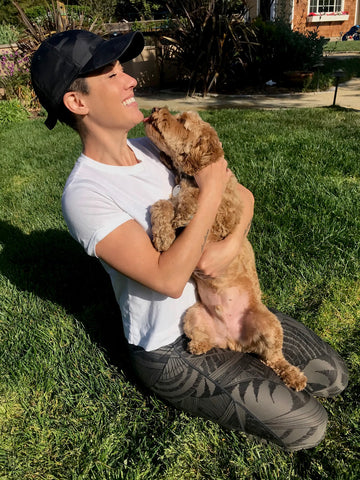 Mariel holding her dog while he tries to kiss her.